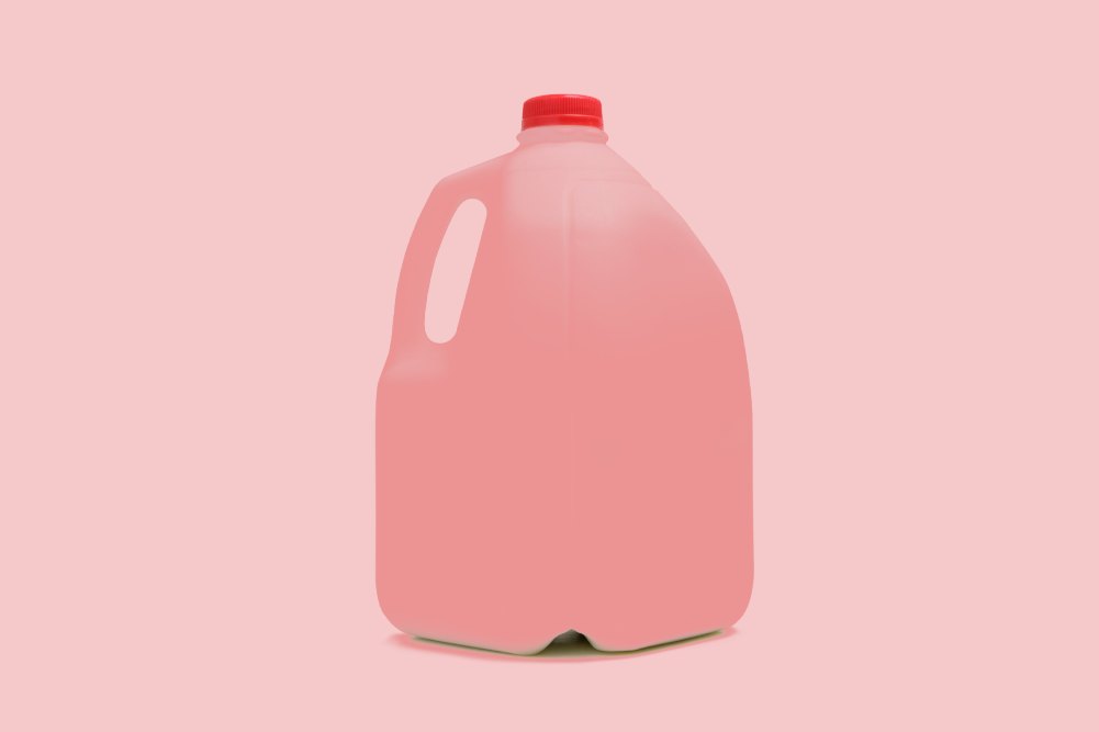 a one gallon plastic of red liquid with a pink background
