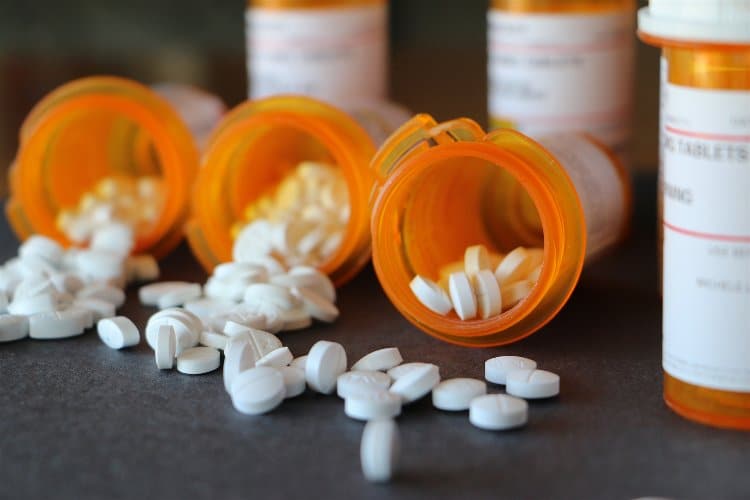 Background image of prescription medications dumped out on a countertop.
