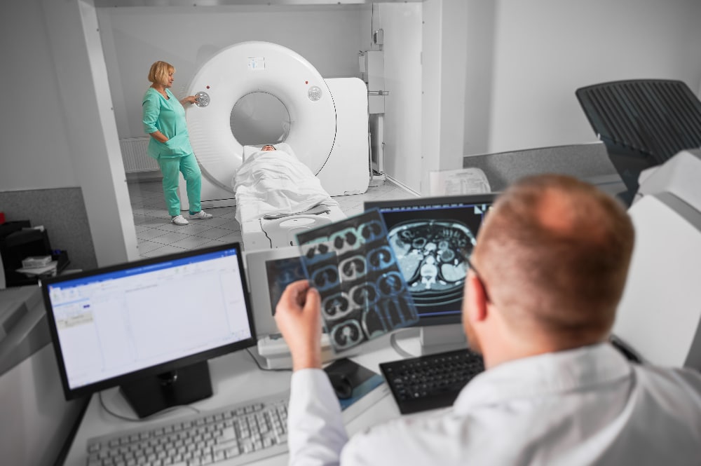 Medical computed tomography or MRI scanner. Back view of male doctor sitting at computer, nurse making MRI. Focus on nurse. Specialists working in hospital, studying results