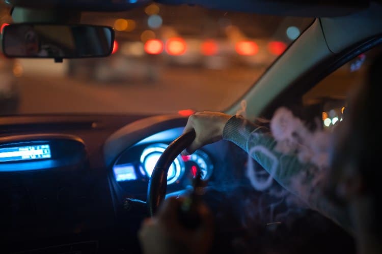 a man makes smoke rings in the car. 
