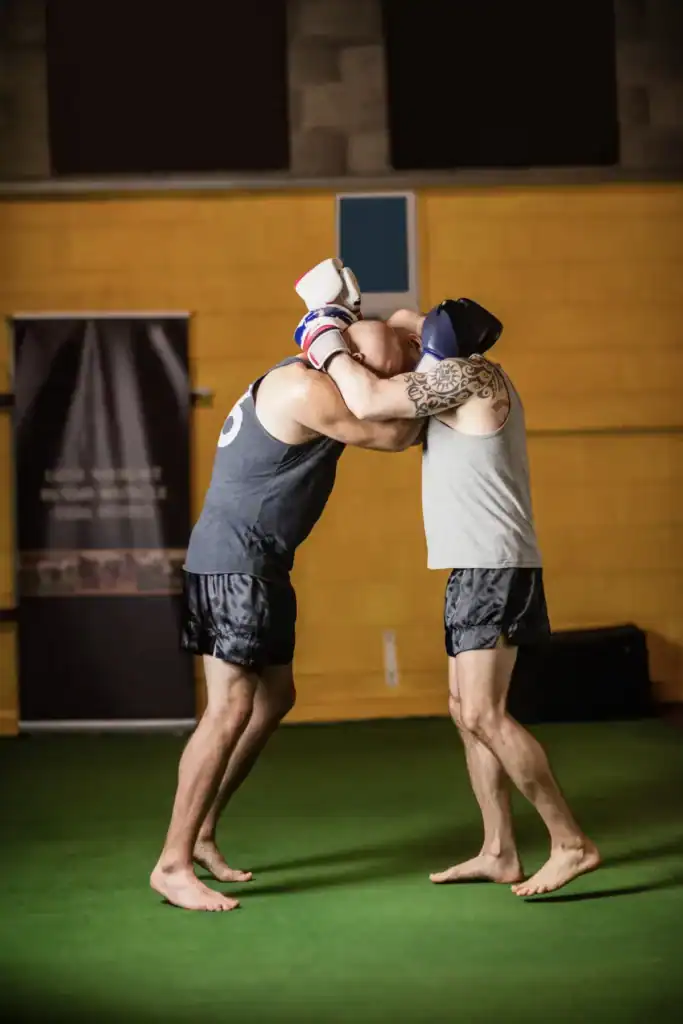 Two men practicing MMA techniques in a gym for recovery and fitness.