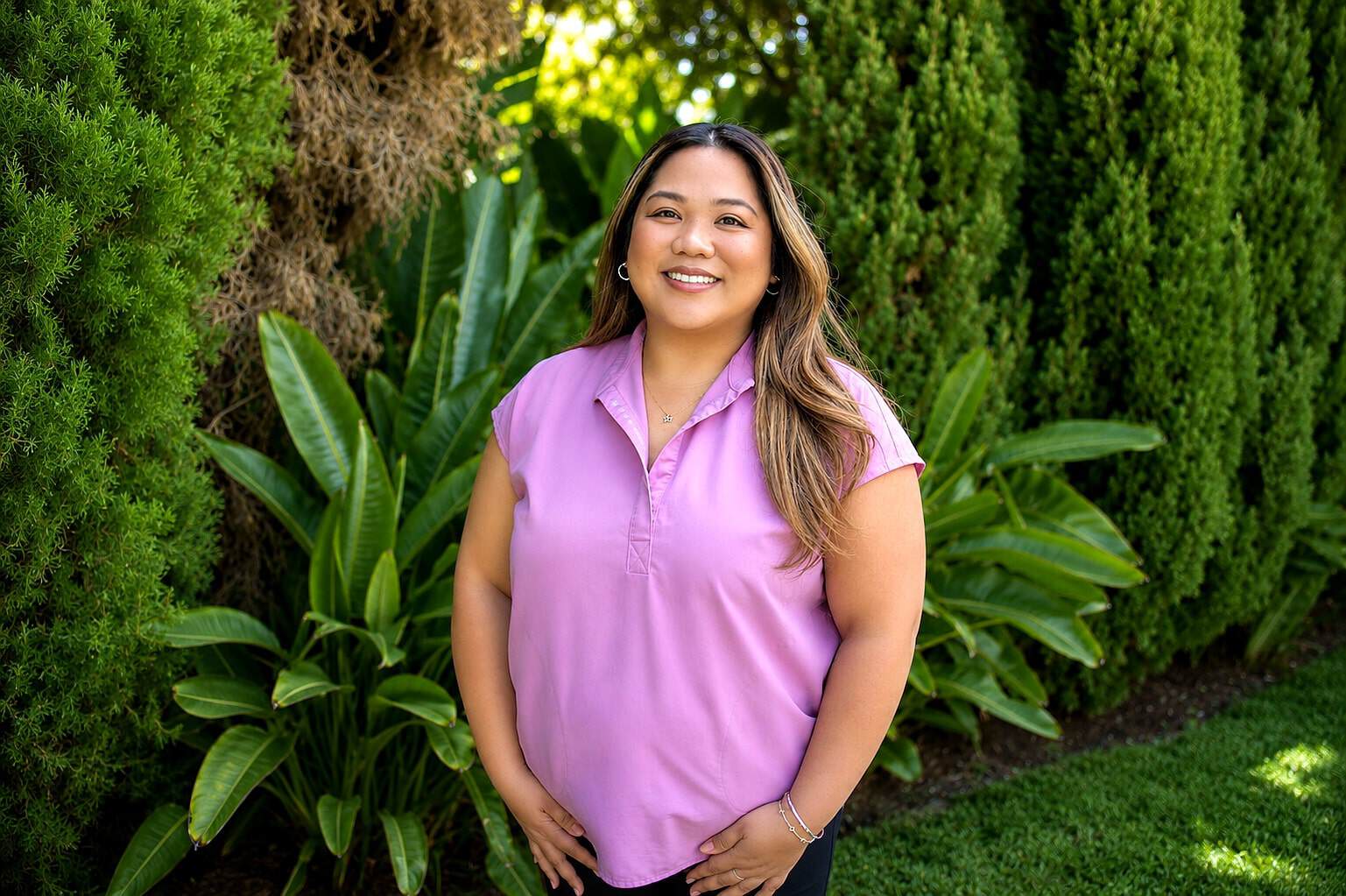 Smiling woman in pink polo shirt outdoors at Healthy Life Recovery.