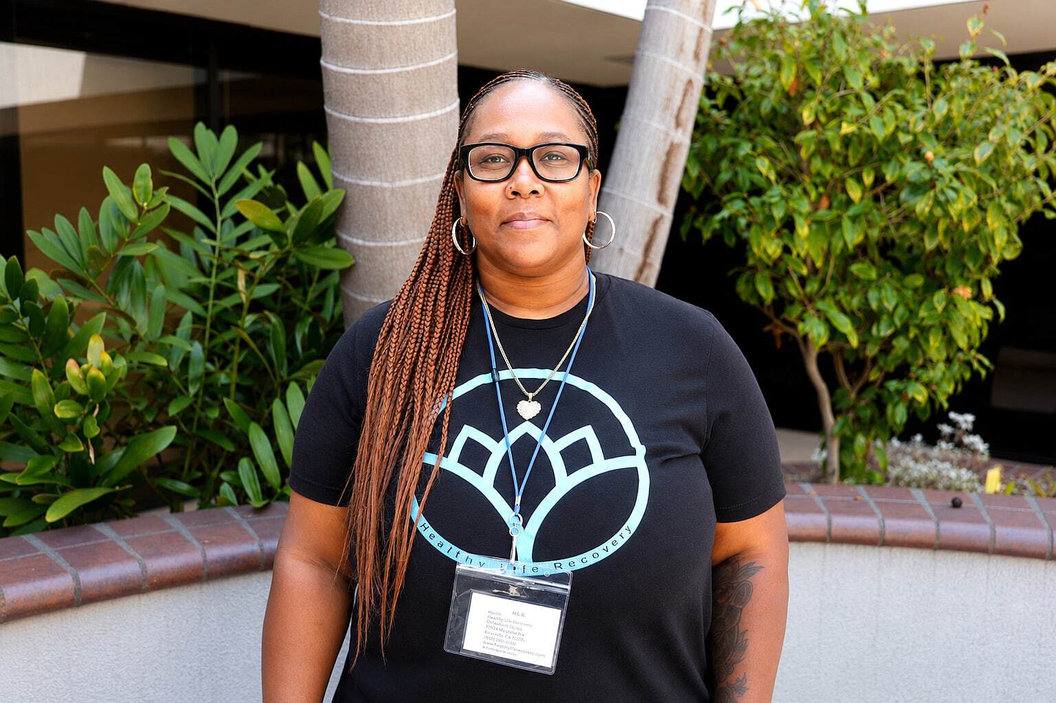 Female staff member at Healthy Life Recovery with glasses and name badge.
