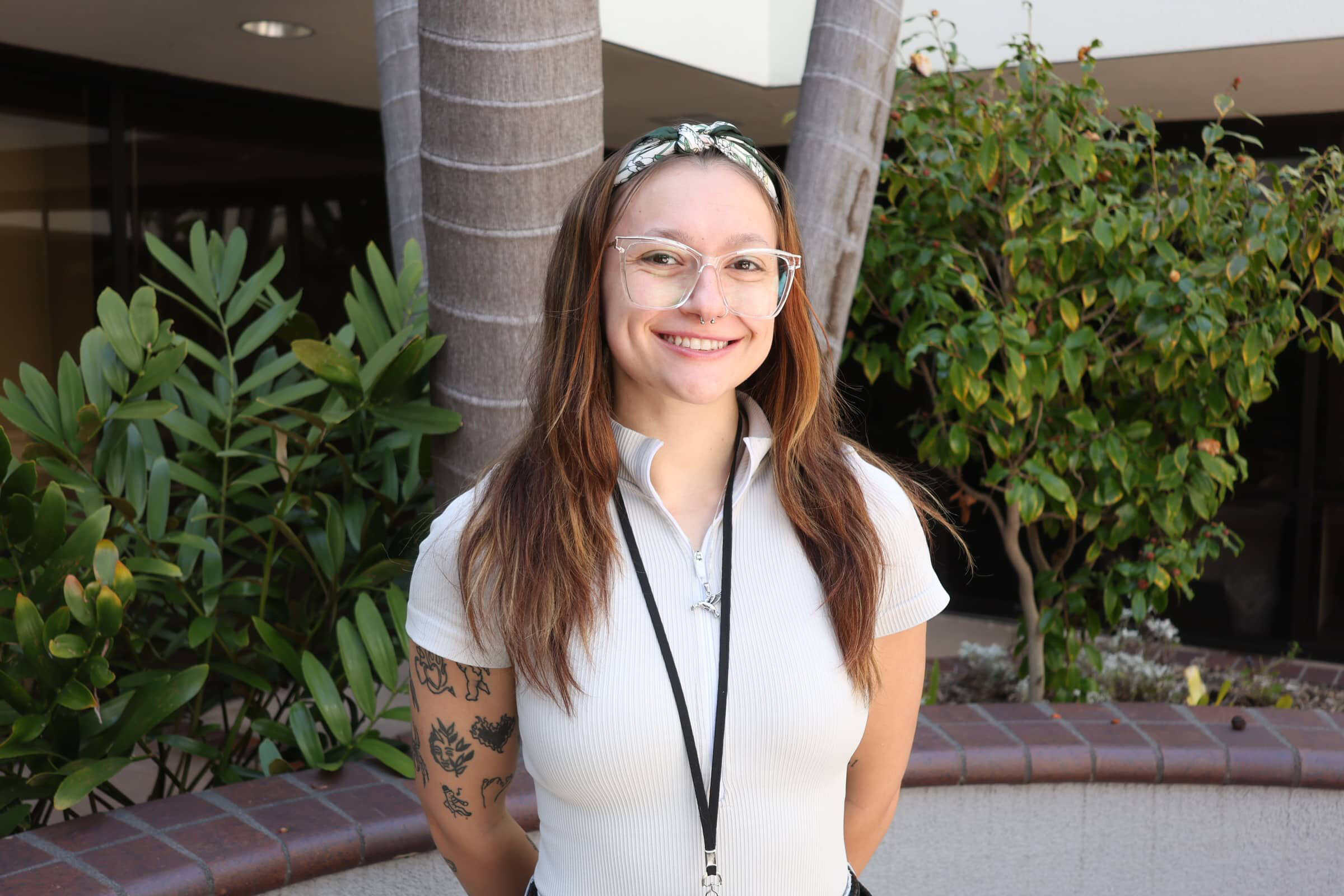 Smiling staff member at Healthy Life Recovery with plants in background.