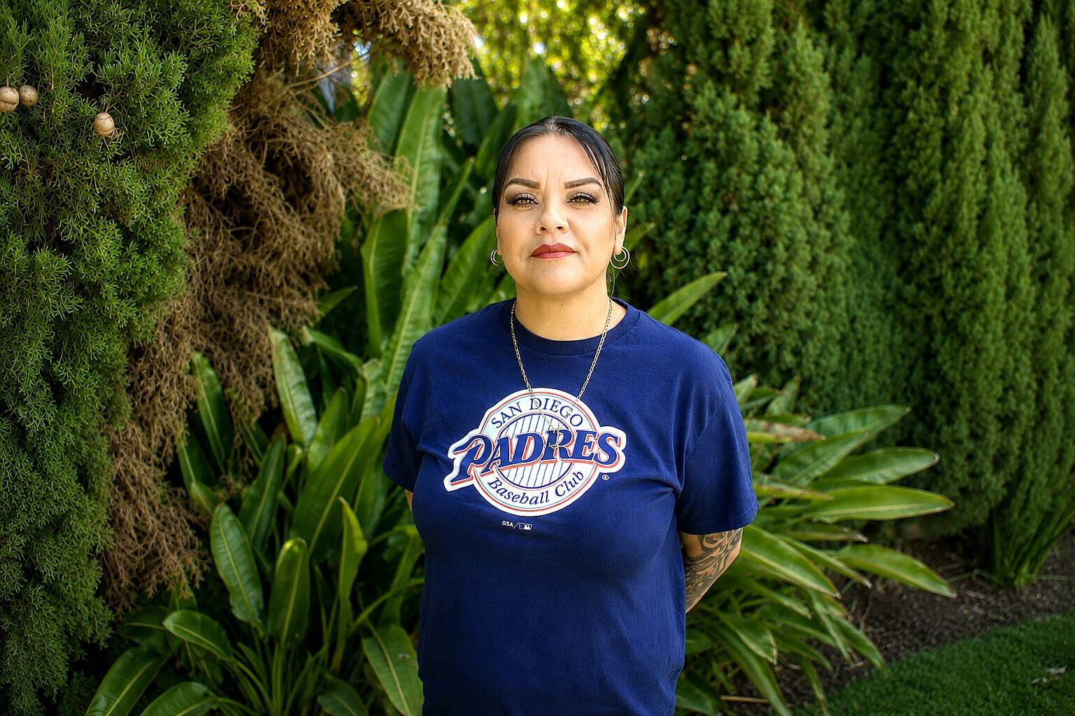 Staff member at Healthy Life Recovery standing outdoors with greenery.